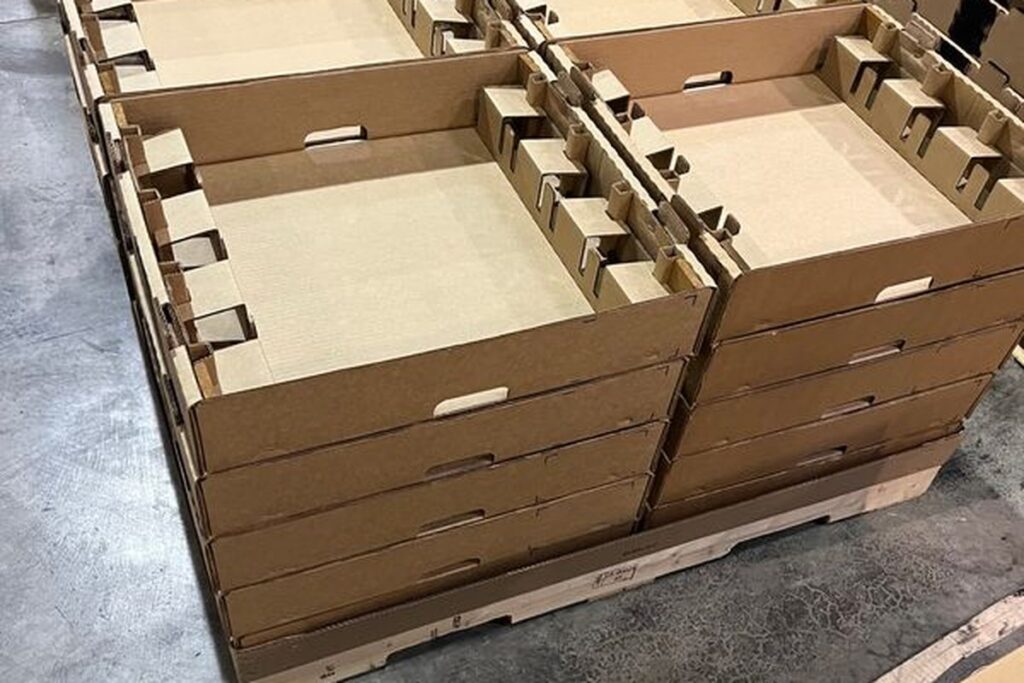 Layered corrugated trays with interlocking dividers, stacked and banded on a pallet