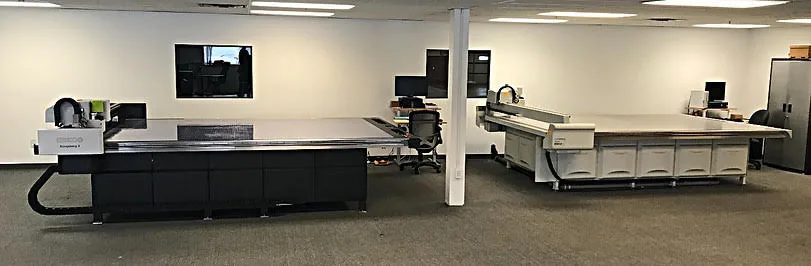 Two Kongsberg CAD cutting tables side by side in a production room